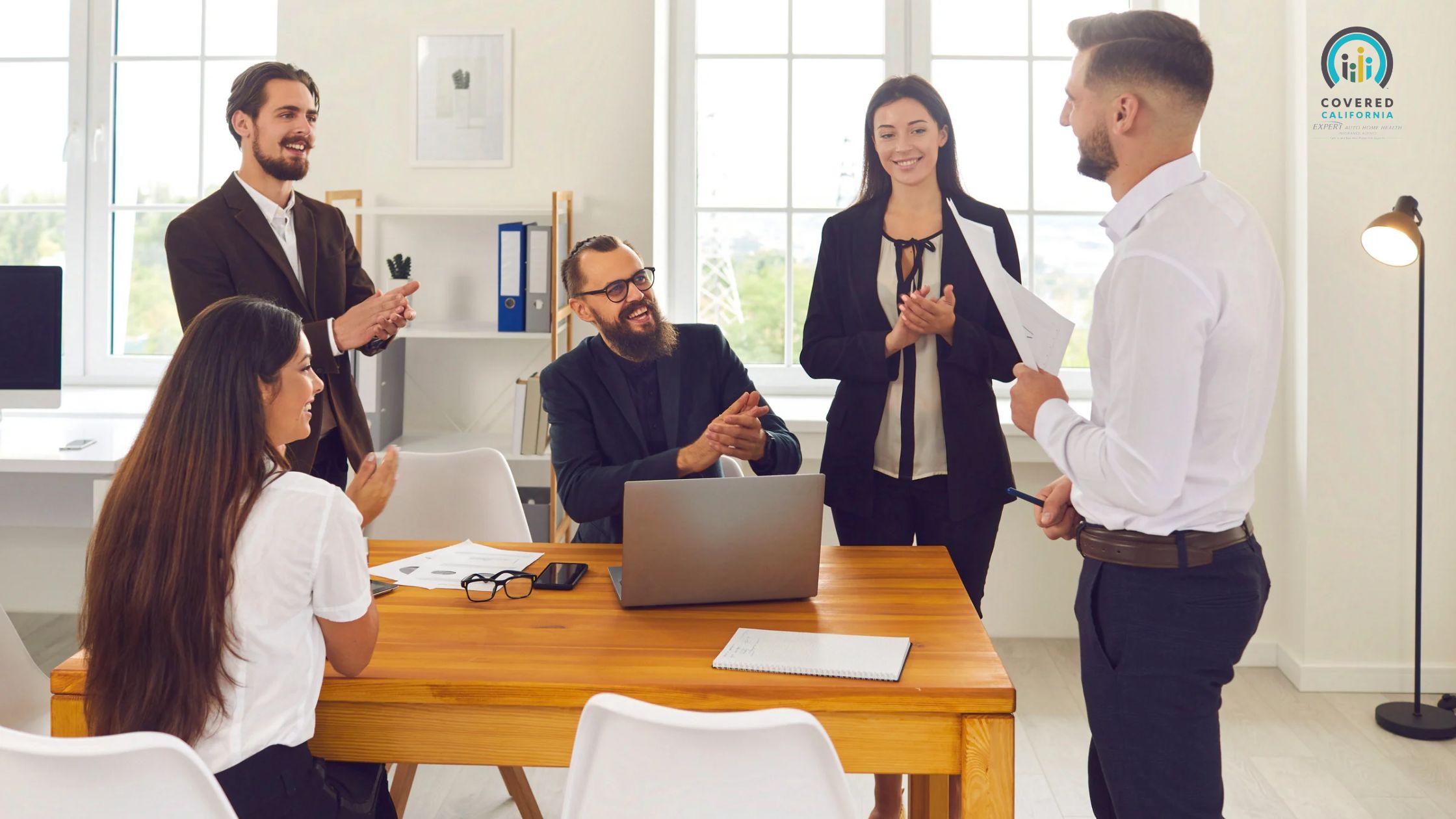 Diverse office team clapping for a smiling colleague