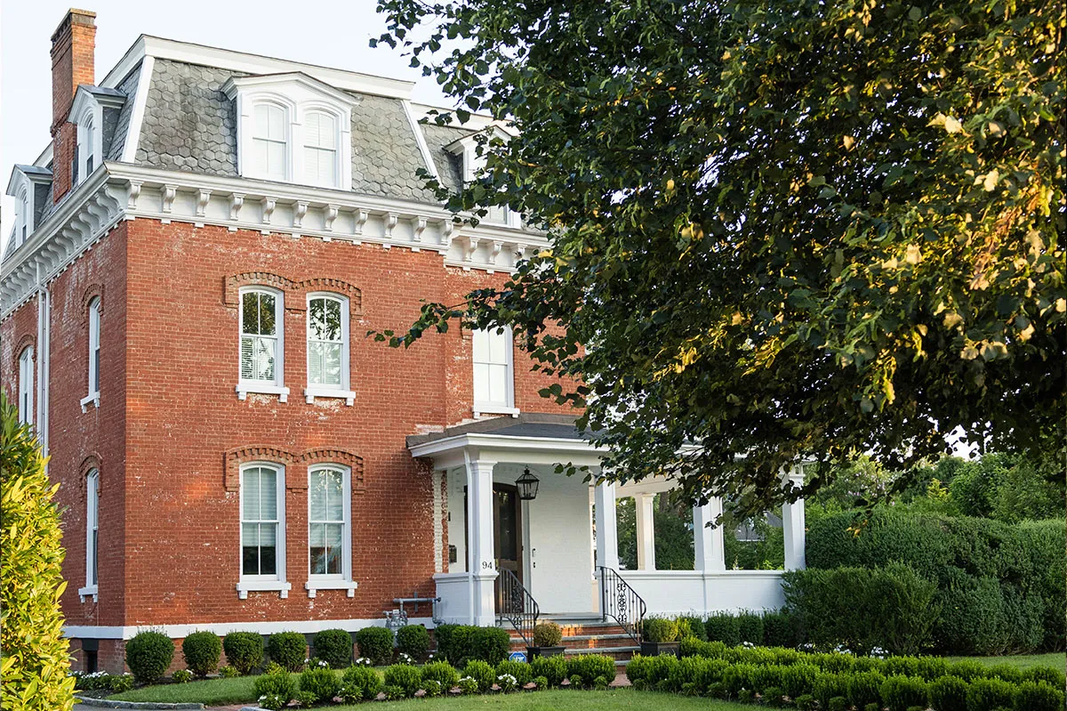 Historic red brick colonial home with white trim and mansard roof